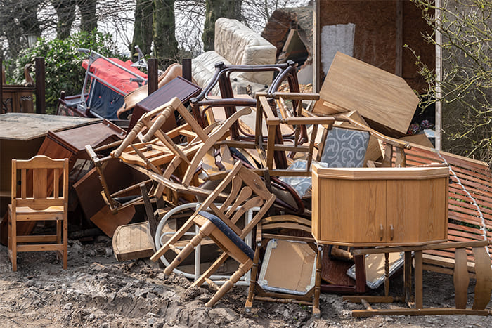 Ein großer Haufen alter Möbel, darunter Stühle, Tische und Schränke, im Freien zur Abholung und umweltgerechten Entsorgung bereit.