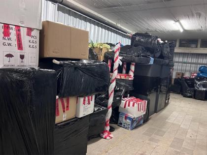 Gestapelte Möbel und Kartons, sicher in schwarzer Folie und mit „Vorsicht Glas“-Markierungen für den Transport vorbereitet