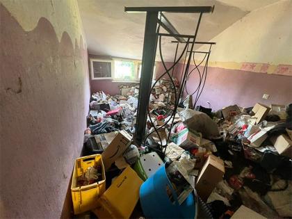 in Raum in einer Messie-Wohnung mit einer Vielzahl von Müll, Kartons und Gegenständen, die auf eine Entrümpelung warten