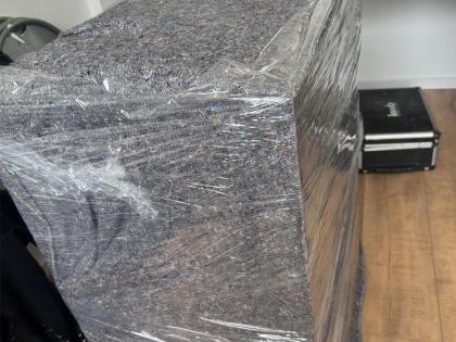 Ein Sofa, sorgfältig mit einer Schutzdecke und transparenter Folie umhüllt, bereit für den Umzug