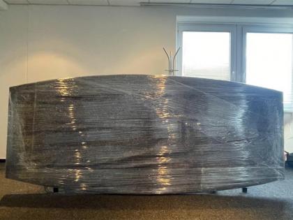 Ein großes Sofa, sorgfältig mit transparenter Schutzfolie umhüllt, bereit für den sicheren Transport
