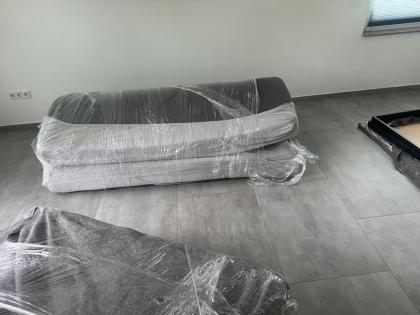 Zwei Sofas, übereinander gestapelt und mit transparenter Schutzfolie sorgfältig verpackt