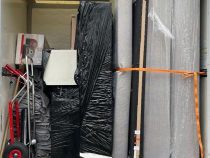 Ein Umzugstransporter, beladen mit verpackten Möbeln, Umzugskartons, einer Sackkarre und Schutzdecken, sorgfältig gesichert