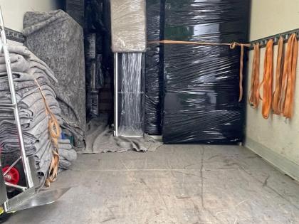 Ein beladener Umzugstransporter mit sorgfältig verpackten Möbeln in schwarzer Folie, Umzugsdecken und Befestigungsgurten